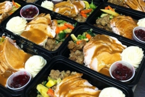 Trays of turkey, mashed potatoes, veggies, stuffing and cranberry sauce